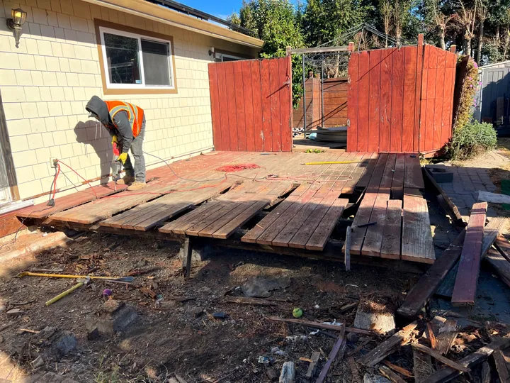 Deck boards lifted off the joists part-way through a backyard deck removal