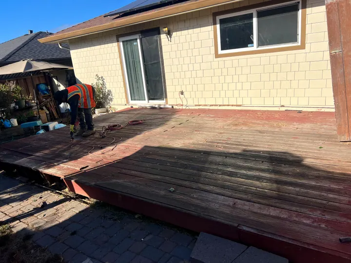 Mosso crew member cutting up an old backyard deck with a saw