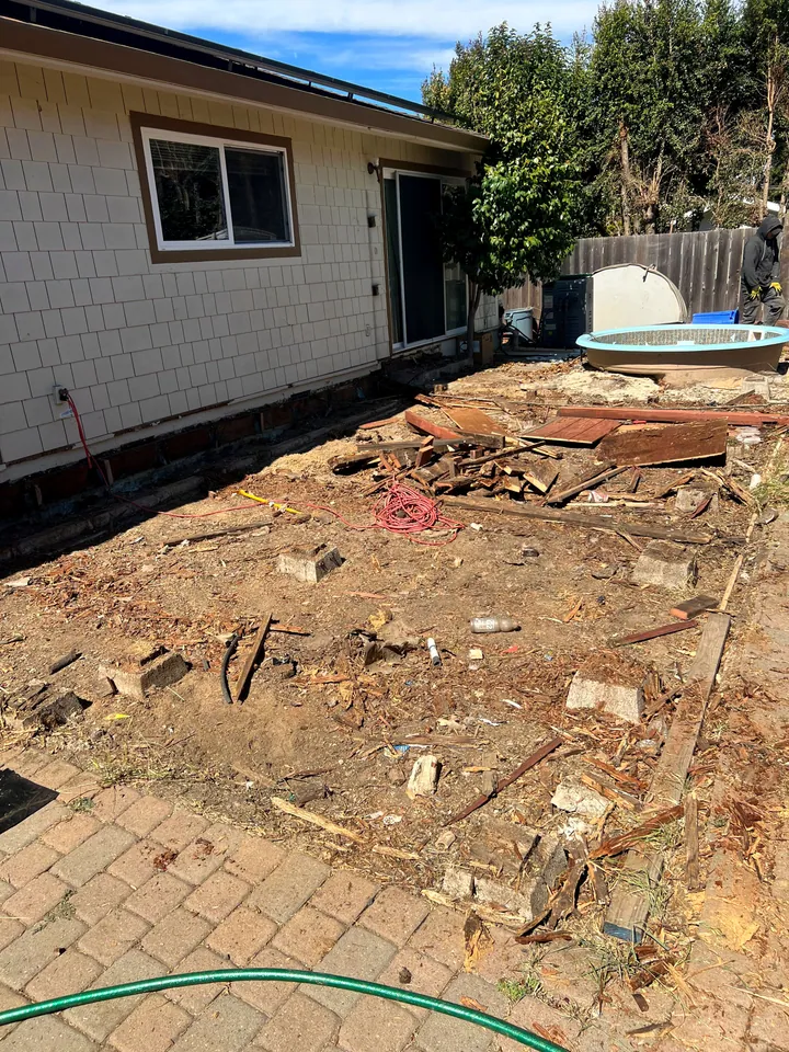 Old hot tub clear of the deck, with the torn-out decking stacked ready to load