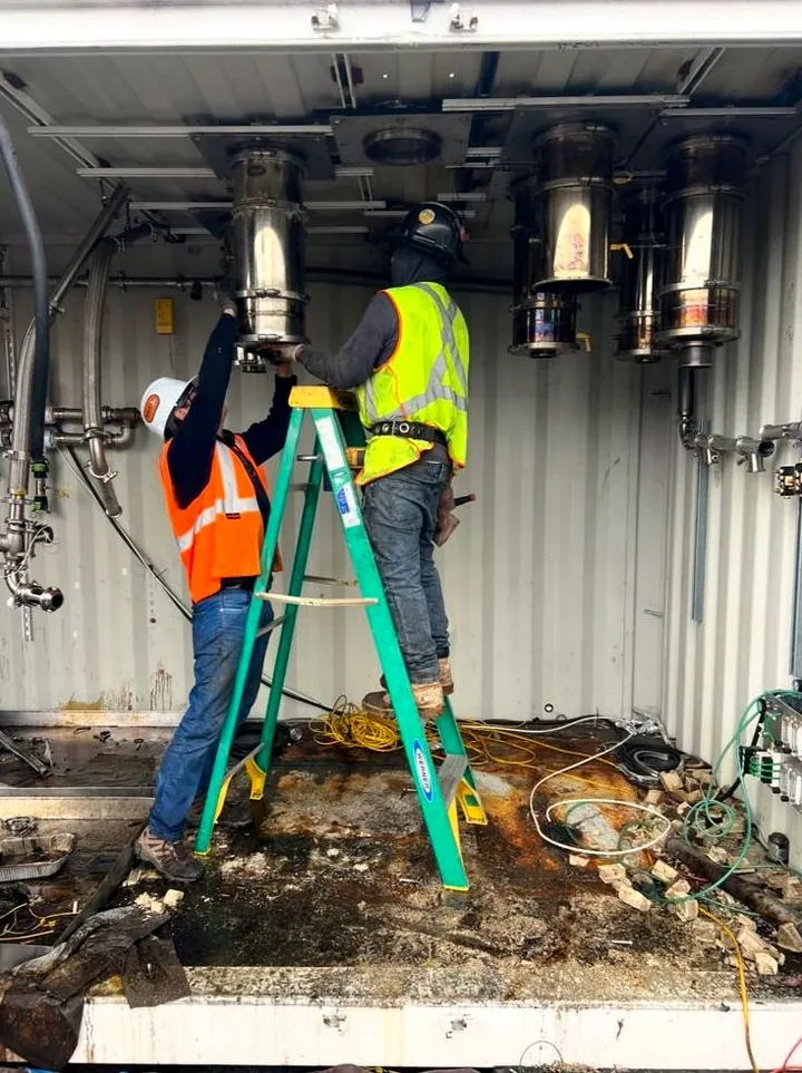 Two Mosso crew members removing equipment inside a container