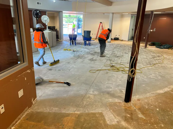 Crew sweeping a stripped commercial interior after demolition