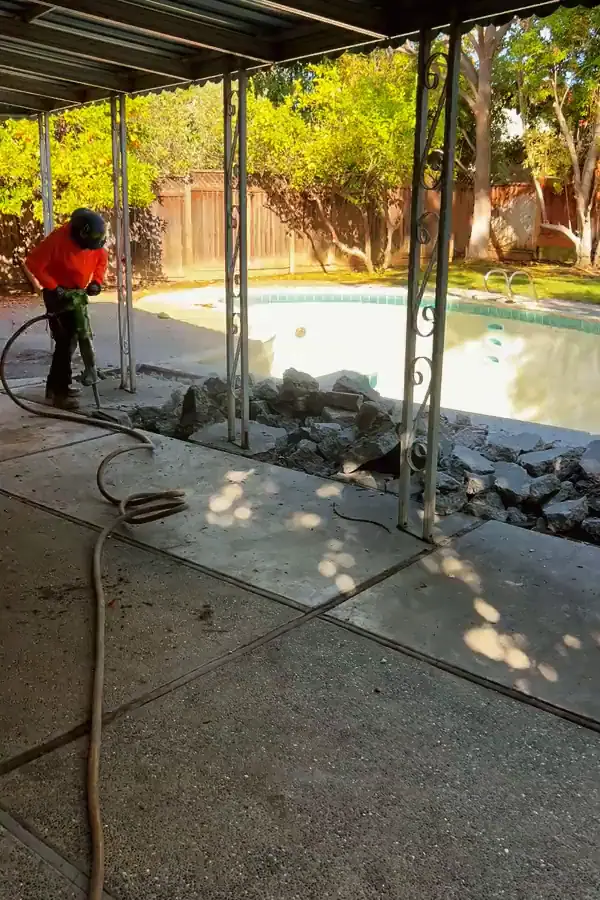 Mosso crew member breaking up the concrete deck beside an in-ground pool