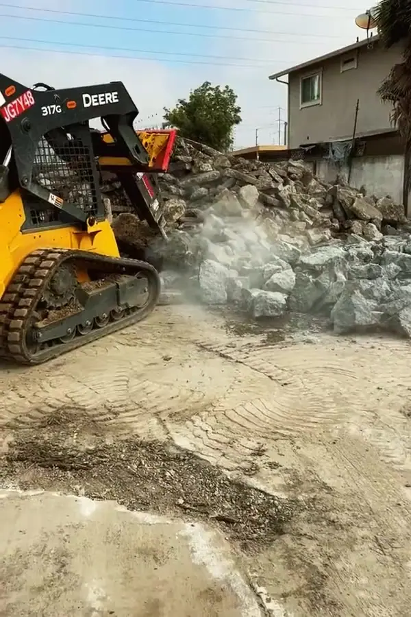 Skid steer pushing broken concrete into a pile for loading