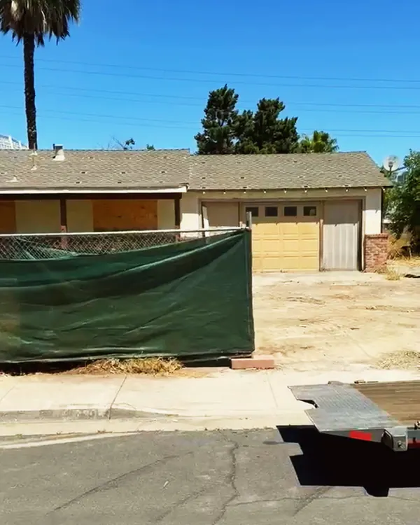 Old garage and house behind construction fencing, before demolition