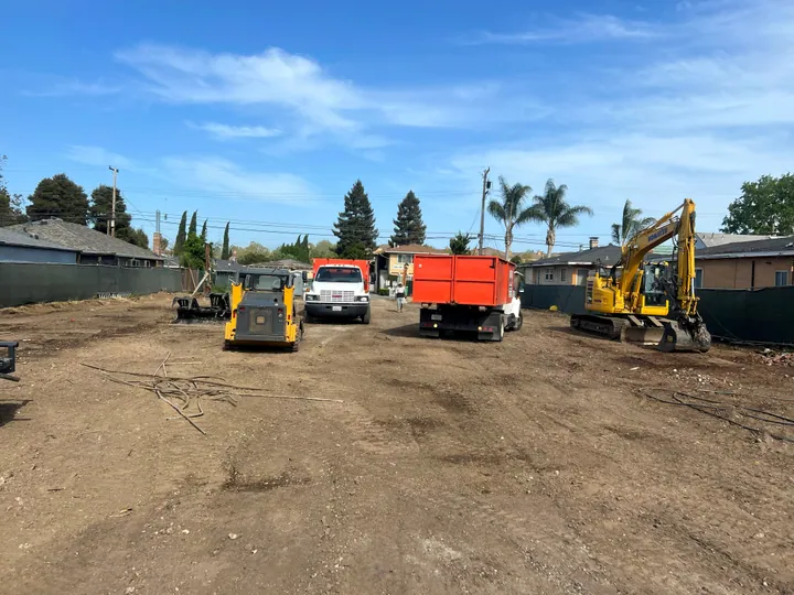 Cleared lot with Mosso excavators, dump truck and crew trucks
