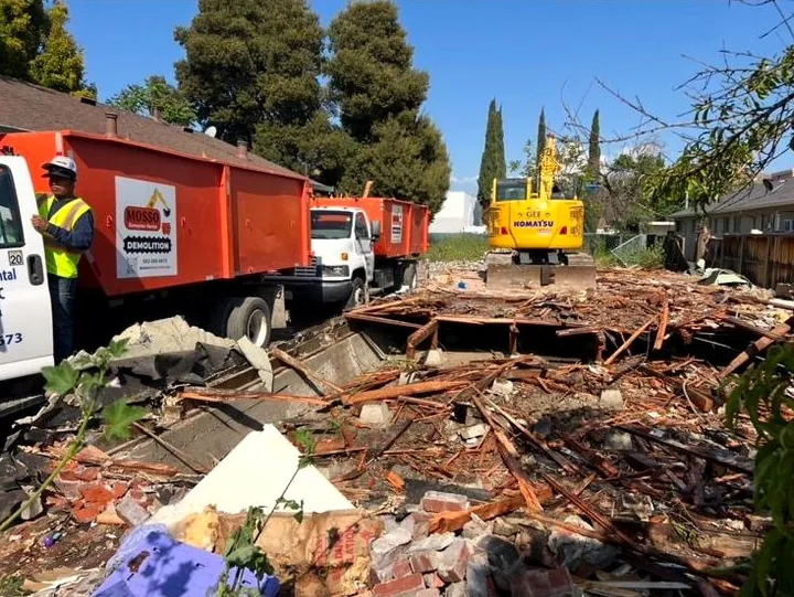 Mosso trucks staged beside a flattened house