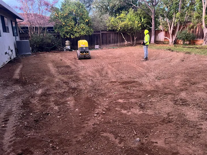 Backyard graded flat after the concrete came out, with a compactor on the dirt